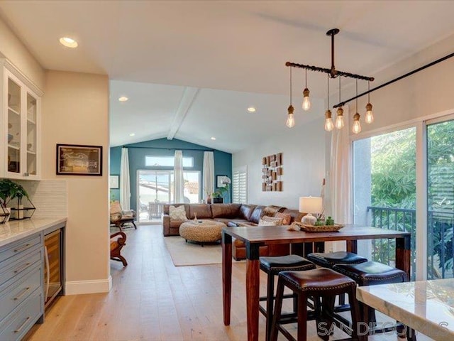 dining room with light hardwood / wood-style flooring, lofted ceiling, and wine cooler