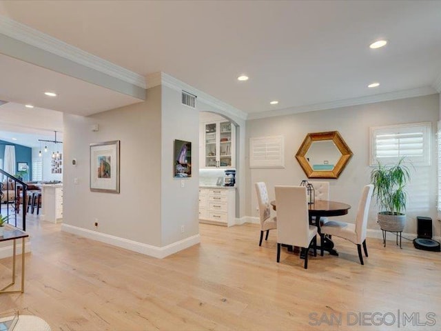 dining space featuring light wood-type flooring and ornamental molding