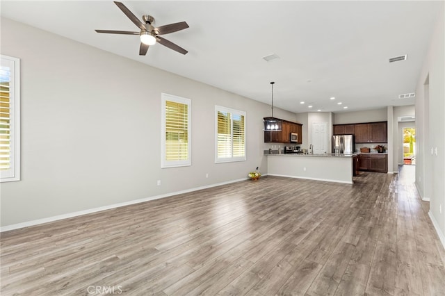 unfurnished living room featuring a ceiling fan, baseboards, and wood finished floors