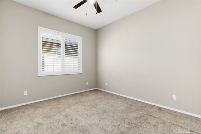 carpeted spare room with baseboards and a ceiling fan