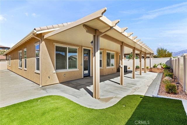 rear view of house with a fenced backyard, stucco siding, and a patio