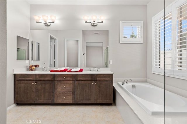 bathroom with double vanity, visible vents, a sink, and a garden tub
