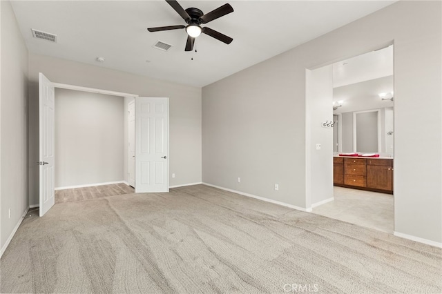 unfurnished bedroom featuring baseboards, ensuite bath, light colored carpet, and visible vents