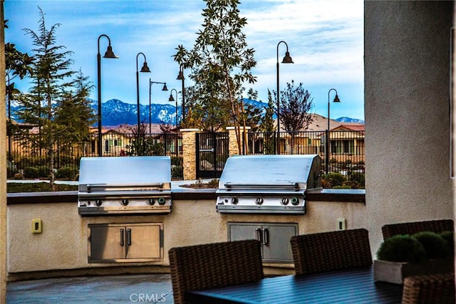 view of patio / terrace with an outdoor kitchen, area for grilling, a mountain view, and fence