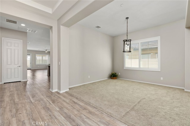 carpeted spare room with baseboards, visible vents, and wood finished floors