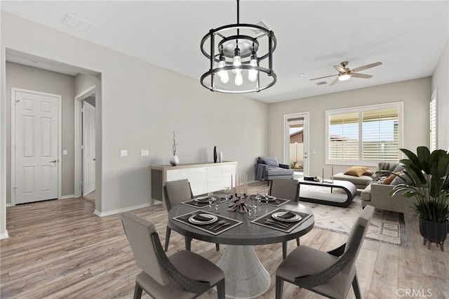 dining space with baseboards, ceiling fan with notable chandelier, light wood-style floors, and visible vents