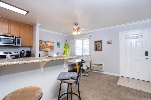 kitchen with light colored carpet, an AC wall unit, a kitchen bar, stainless steel appliances, and ornamental molding