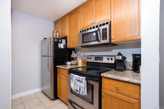 kitchen featuring light stone counters, appliances with stainless steel finishes, and light tile patterned flooring