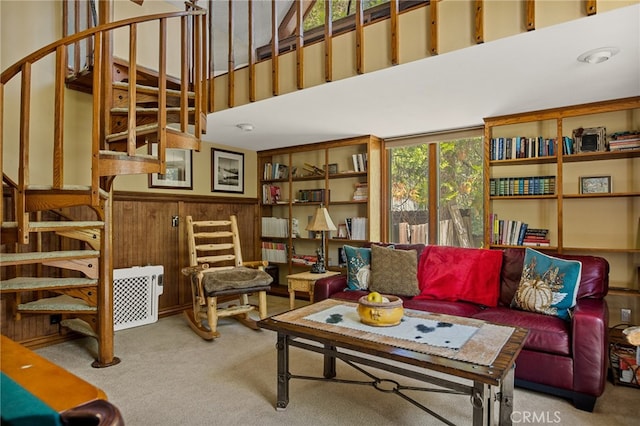 carpeted living room with a towering ceiling, wood walls, and a healthy amount of sunlight