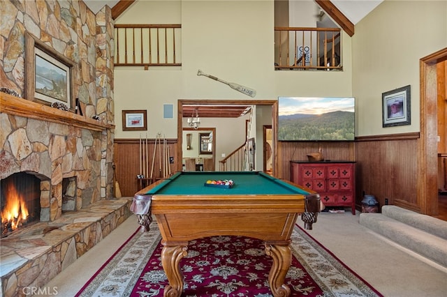 rec room featuring pool table, wood walls, high vaulted ceiling, carpet, and a stone fireplace