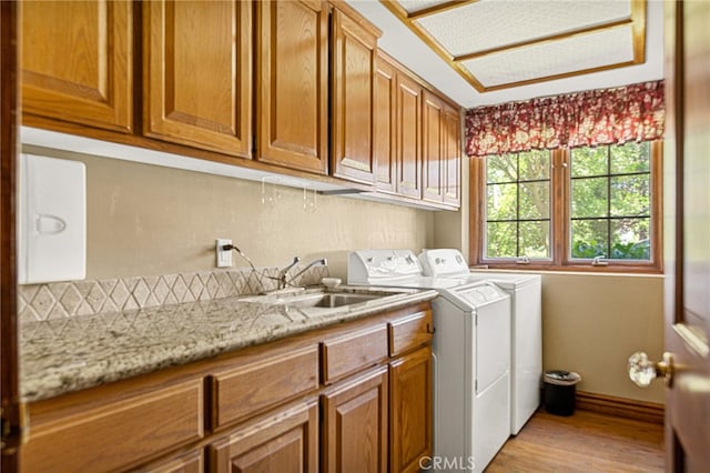 laundry room featuring cabinets, light wood-type flooring, washer and clothes dryer, and sink