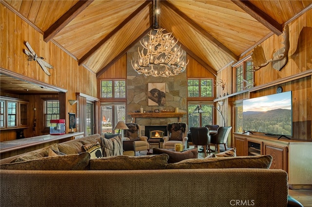 living room with a notable chandelier, wooden ceiling, high vaulted ceiling, and a stone fireplace