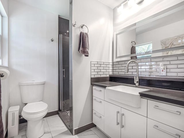 bathroom featuring vanity, toilet, a shower with door, and decorative backsplash