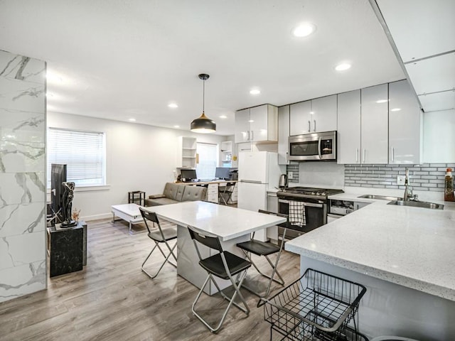 kitchen featuring decorative light fixtures, stainless steel appliances, a kitchen breakfast bar, and white cabinets