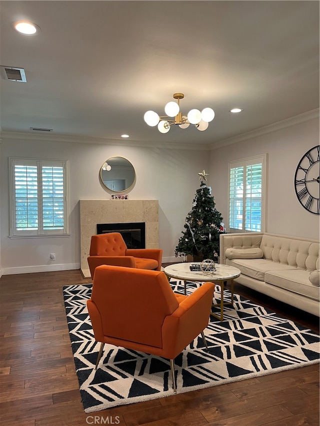 living room with ornamental molding, a chandelier, dark hardwood / wood-style floors, and a fireplace