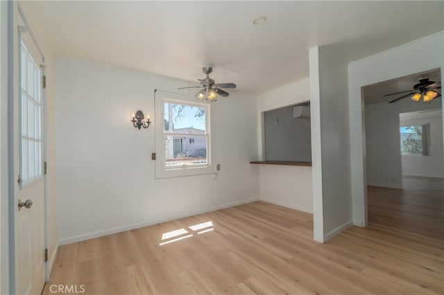 unfurnished room with ceiling fan, light hardwood / wood-style floors, and a wall mounted AC