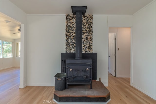 room details featuring wood-type flooring, crown molding, ceiling fan, and a wood stove