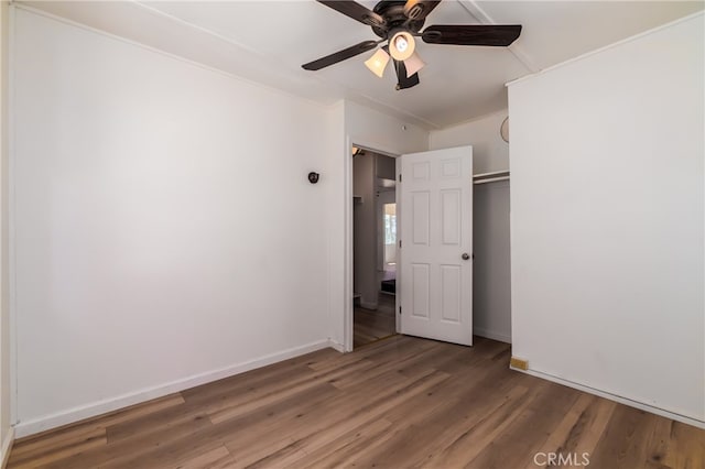 unfurnished bedroom with ornamental molding, dark hardwood / wood-style flooring, ceiling fan, and a closet