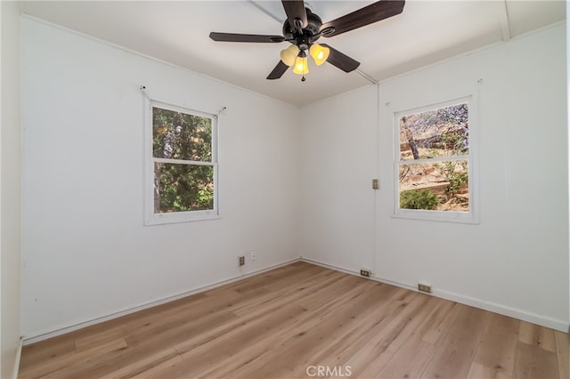 empty room featuring a wealth of natural light, ceiling fan, and light wood-type flooring