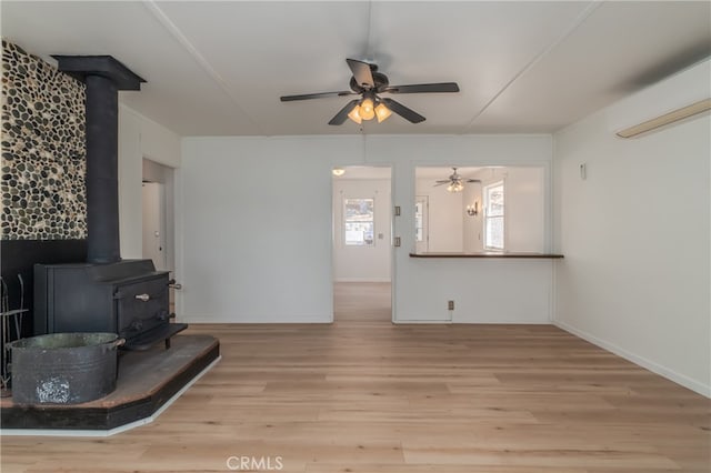 living room featuring ceiling fan, light hardwood / wood-style flooring, and a wood stove