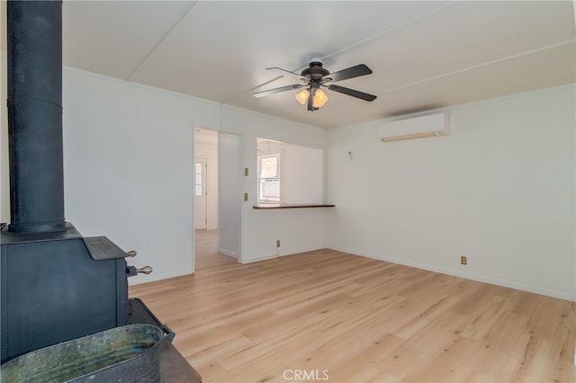 living room with light hardwood / wood-style flooring, a wood stove, ceiling fan, and a wall mounted AC