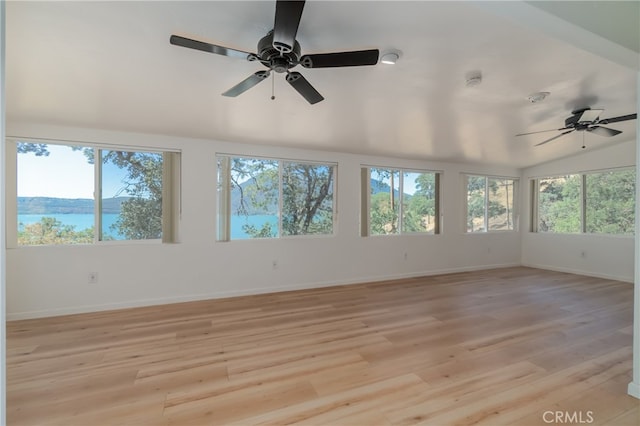 unfurnished sunroom with a water view, vaulted ceiling, ceiling fan, and a healthy amount of sunlight