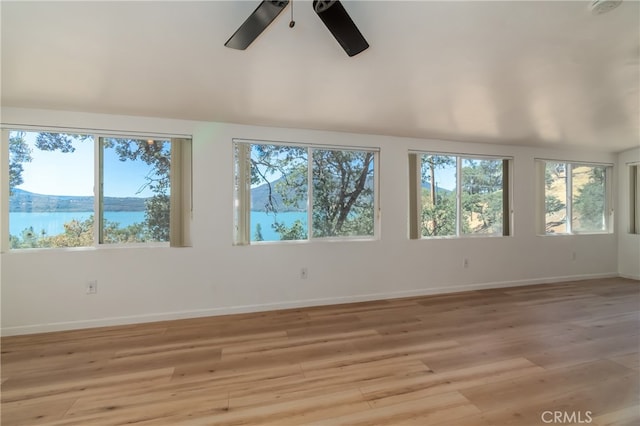 spare room with ceiling fan, light wood-type flooring, a water view, and a wealth of natural light