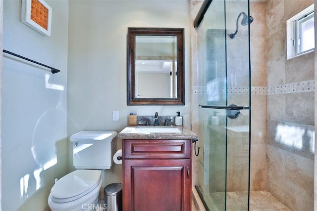 bathroom featuring a shower with door, vanity, and toilet