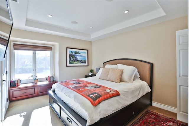 bedroom with light carpet and a tray ceiling