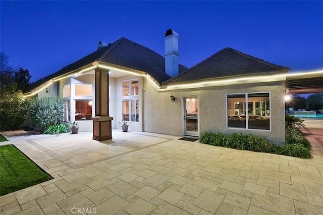 back house at night featuring a patio