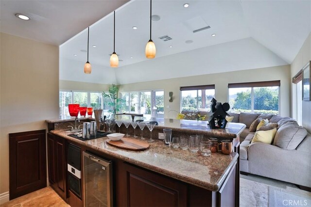 kitchen featuring pendant lighting, plenty of natural light, stone counters, and beverage cooler