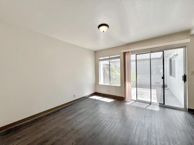 spare room featuring a textured ceiling and dark hardwood / wood-style floors