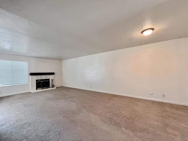 unfurnished living room with a brick fireplace, a textured ceiling, and carpet floors