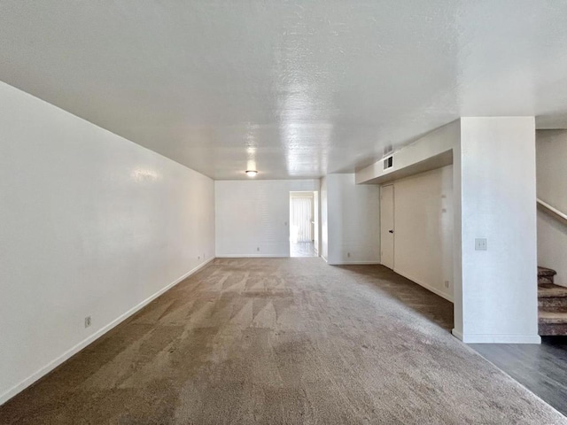 unfurnished living room with dark carpet and a textured ceiling