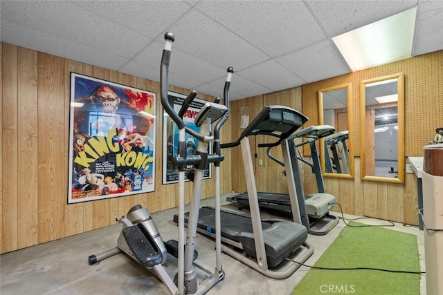 workout room featuring wooden walls and a drop ceiling