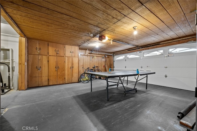 recreation room featuring a garage, wooden ceiling, and concrete flooring