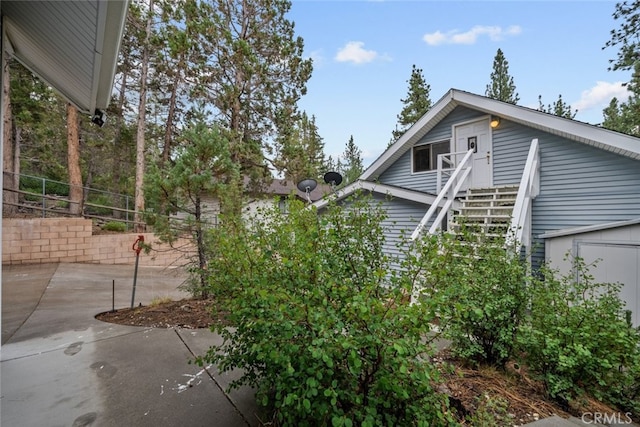 view of side of home with stairs, a patio, and fence