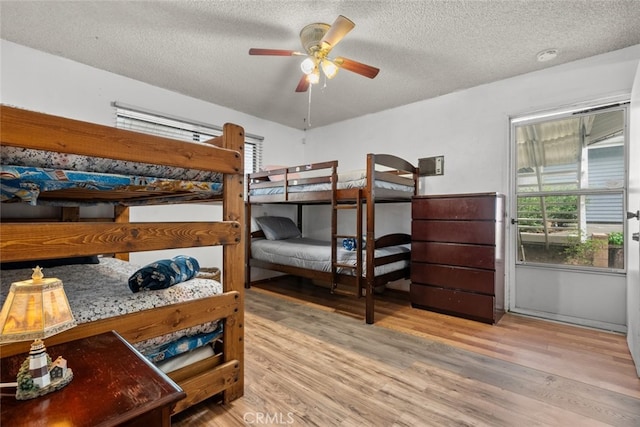 bedroom featuring a textured ceiling, a ceiling fan, and wood finished floors