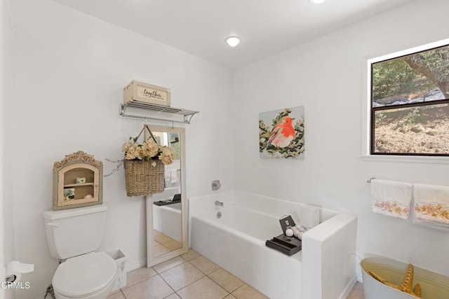 bathroom with a tub to relax in, toilet, and tile patterned floors