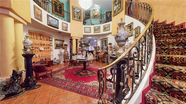 staircase featuring ornate columns, a towering ceiling, and tile patterned flooring