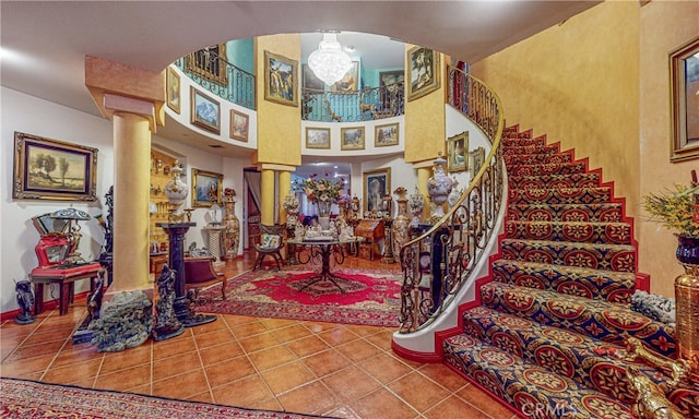 foyer entrance featuring a chandelier, tile patterned floors, and ornate columns