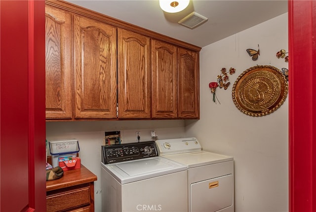 clothes washing area featuring washer and dryer and cabinets