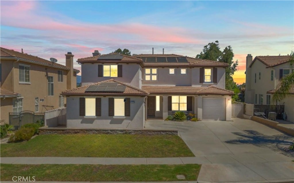 mediterranean / spanish-style home featuring a garage, solar panels, and a yard