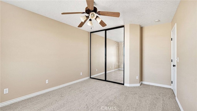 unfurnished bedroom with ceiling fan, a closet, light carpet, and a textured ceiling