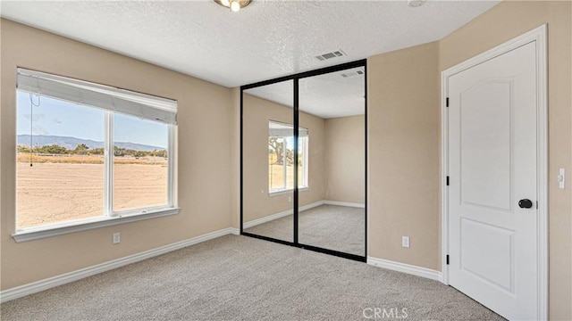 unfurnished bedroom with a closet, a mountain view, light colored carpet, and multiple windows