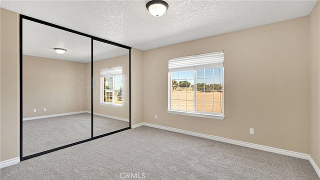 unfurnished bedroom featuring light carpet, a closet, and a textured ceiling