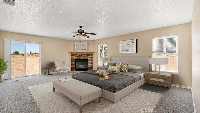 carpeted bedroom with ceiling fan, access to outside, a fireplace, a textured ceiling, and multiple windows