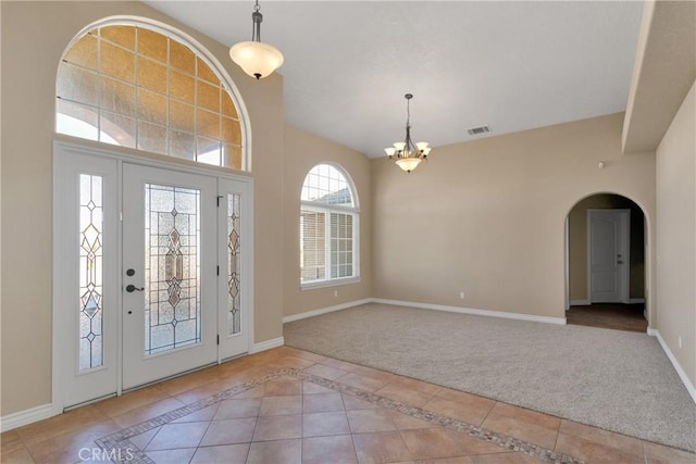 entrance foyer with light tile patterned floors and an inviting chandelier