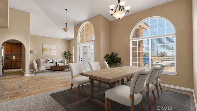 dining space with lofted ceiling, a notable chandelier, and light tile patterned flooring