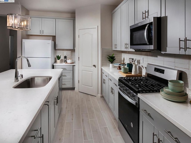 kitchen with stainless steel appliances, sink, decorative backsplash, and gray cabinetry